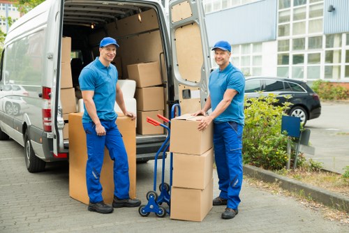 Workers wearing PPE and using a trolley to load waste into a van